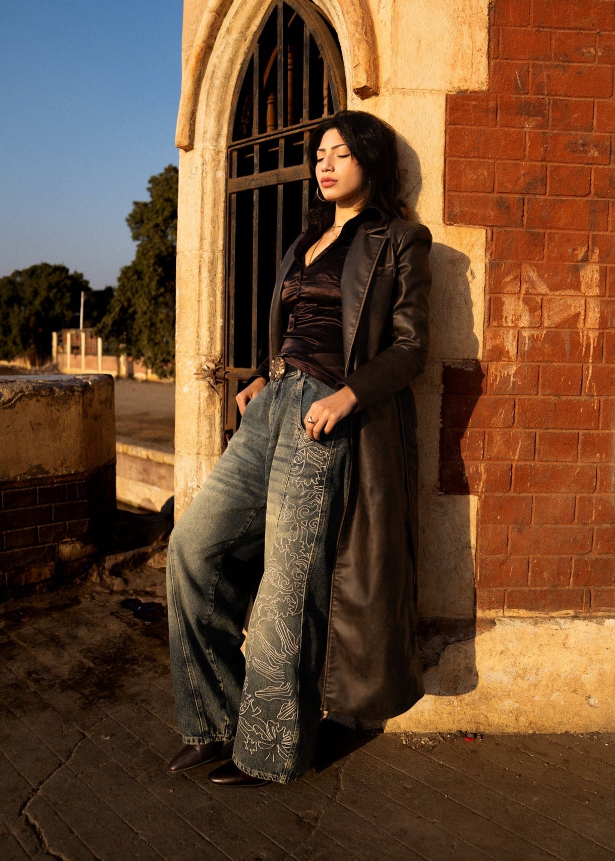 Woman leaning against a brick wall with a building entrance in the background