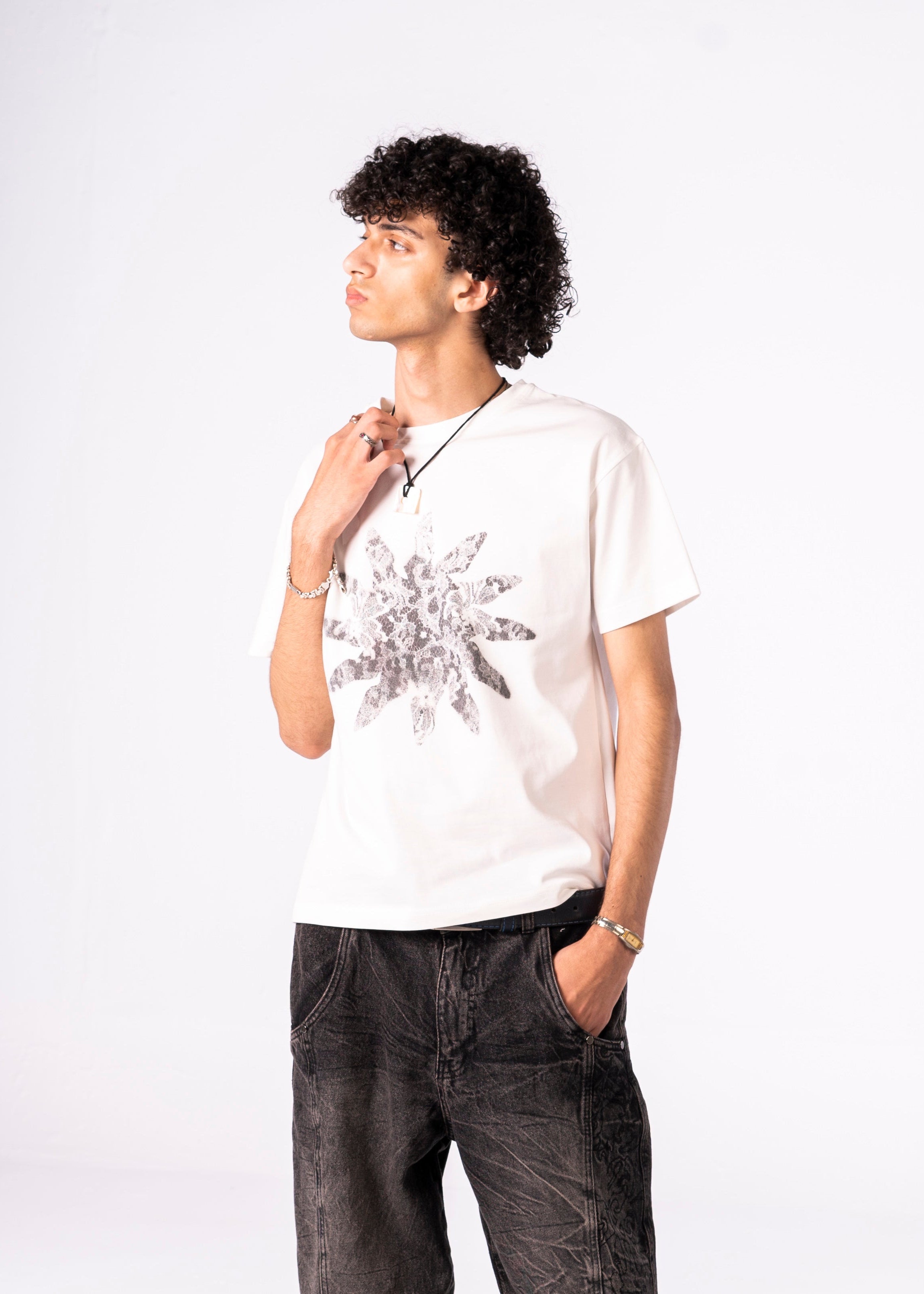 Person wearing a white t-shirt with a black floral design on a plain background