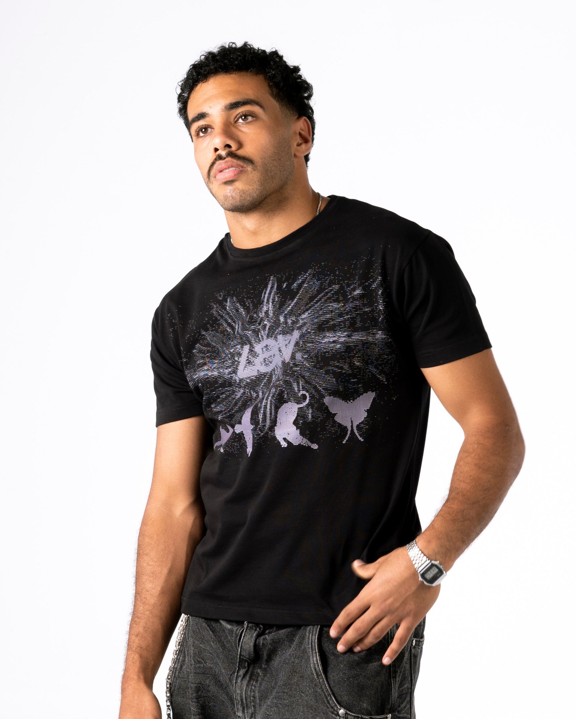 Man wearing a black t-shirt with a graphic design and dark jeans on a white background