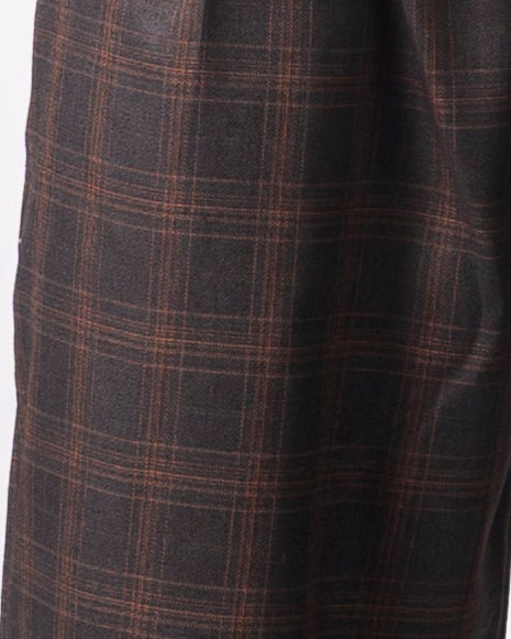 Person wearing plaid shorts and brown boots on a white background