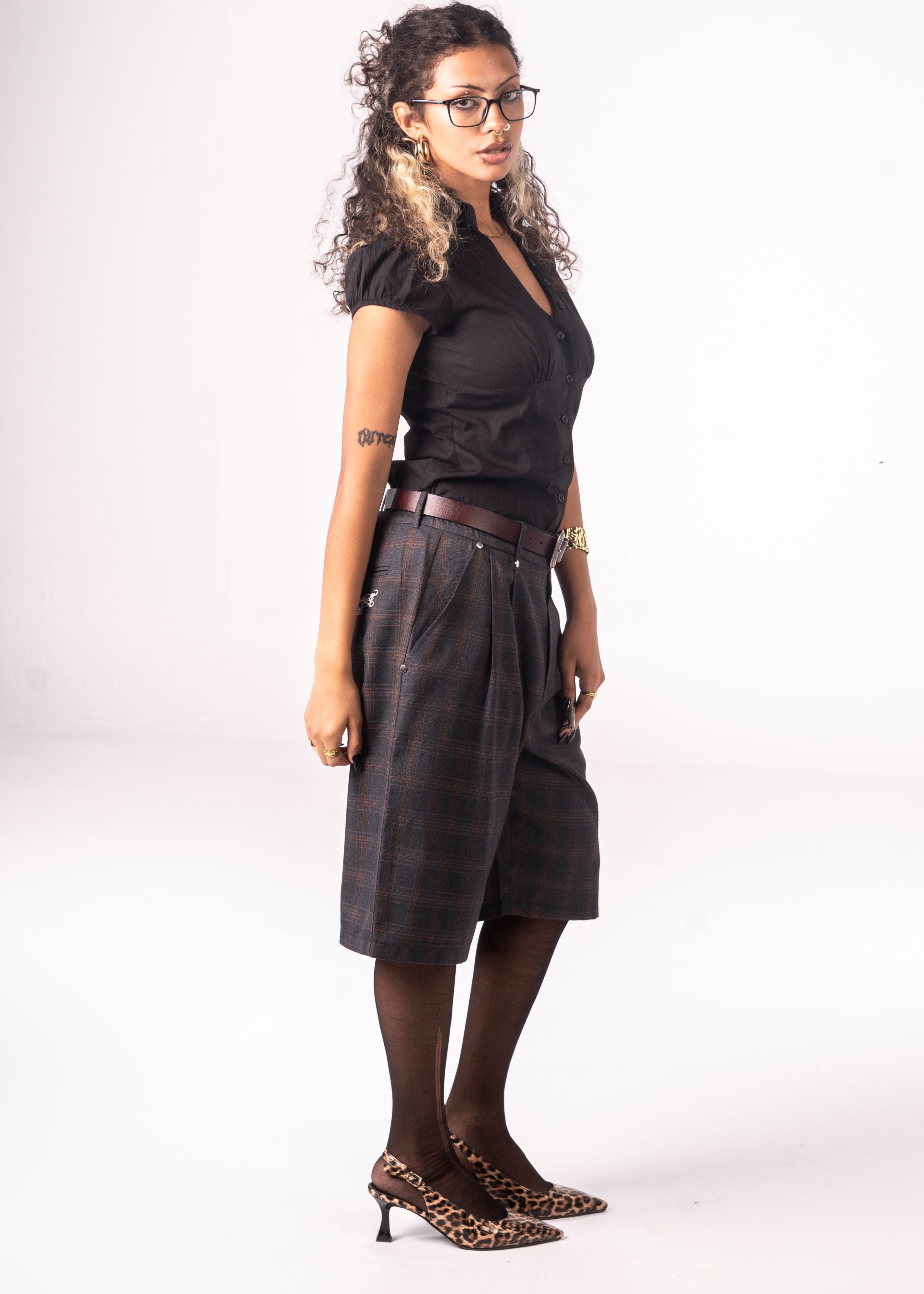 Woman wearing a black top and dark skirt with leopard print shoes on a white background