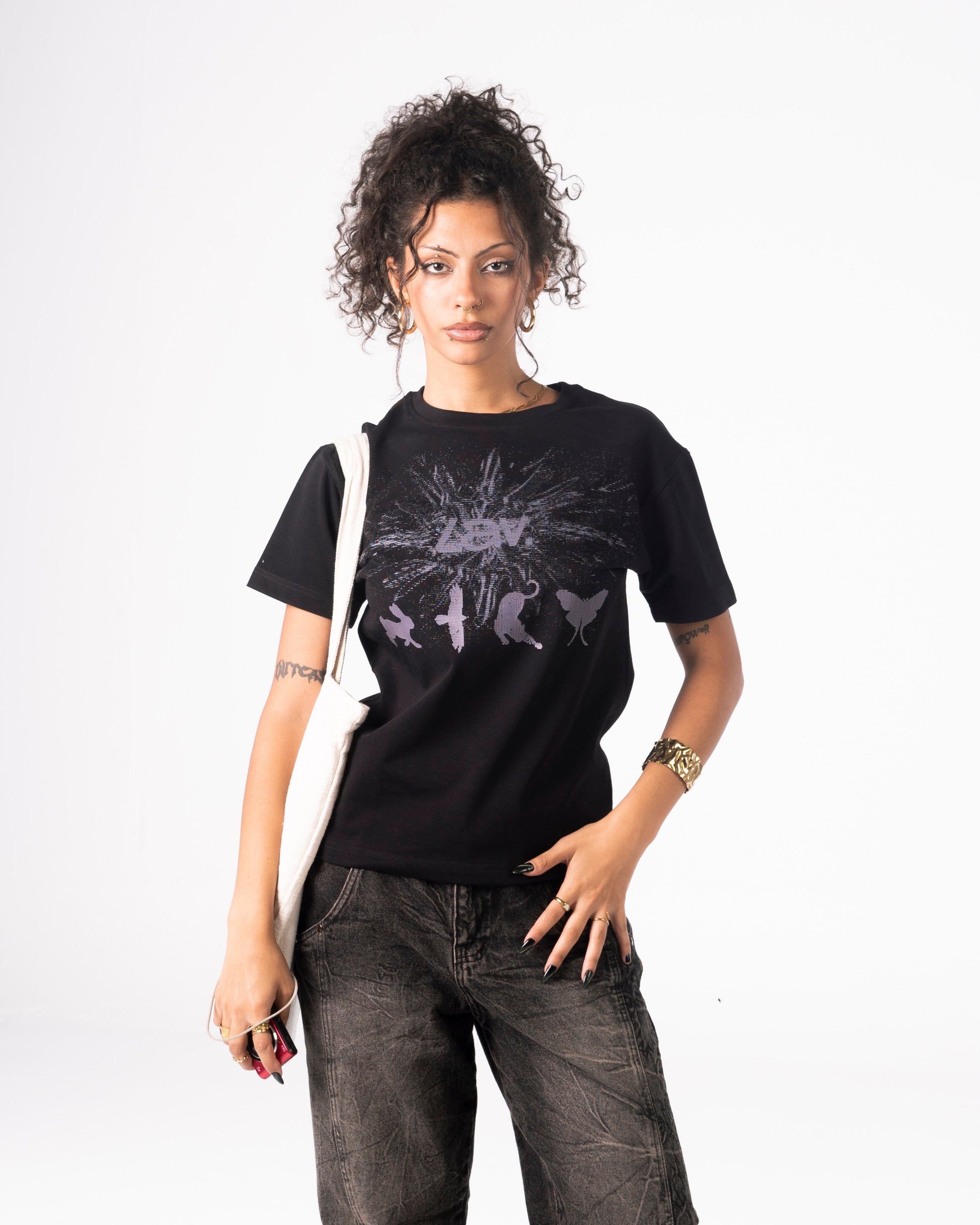 Person wearing a black t-shirt with a graphic design and dark jeans on a white background