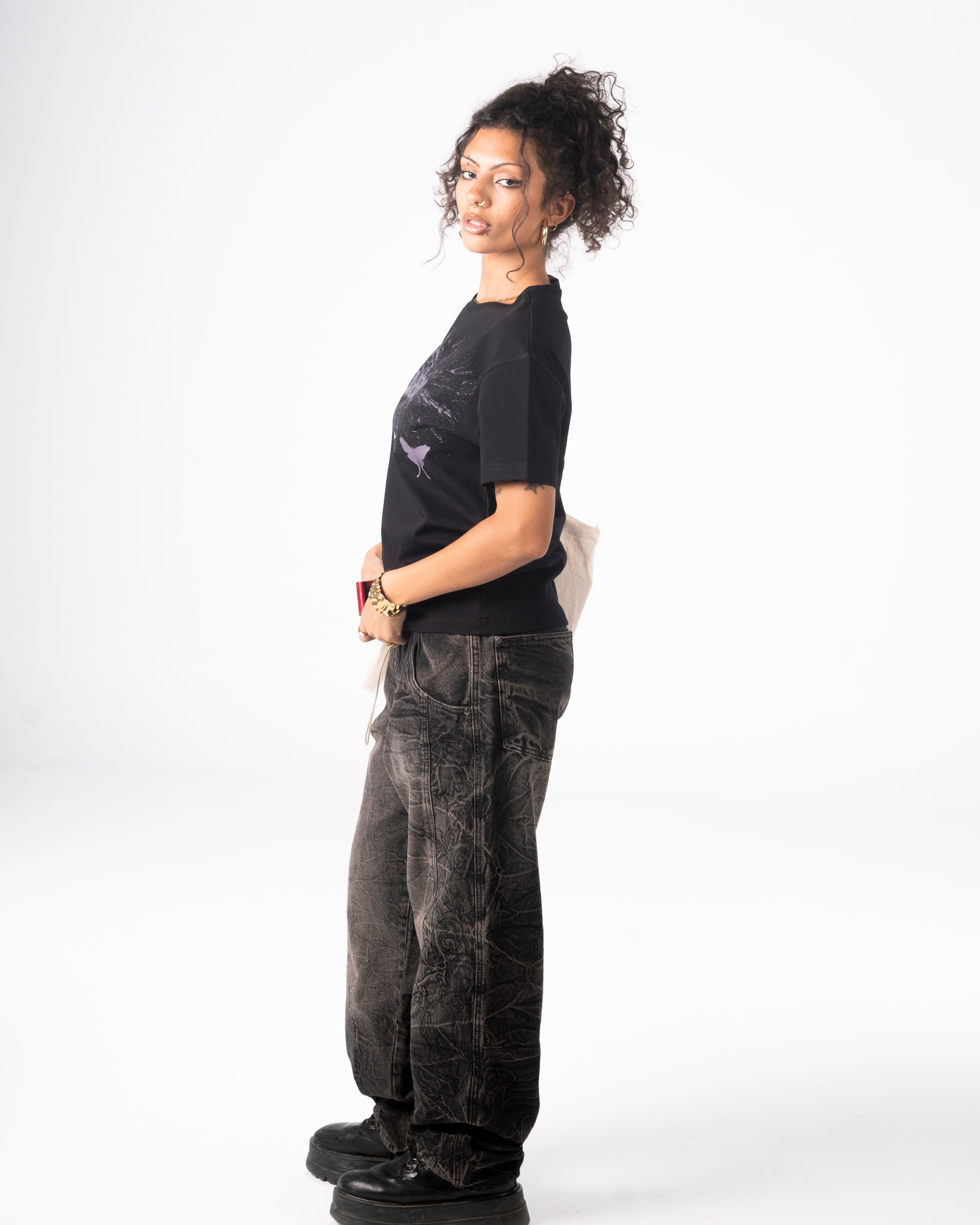 Woman wearing a black t-shirt and dark pants on a white background