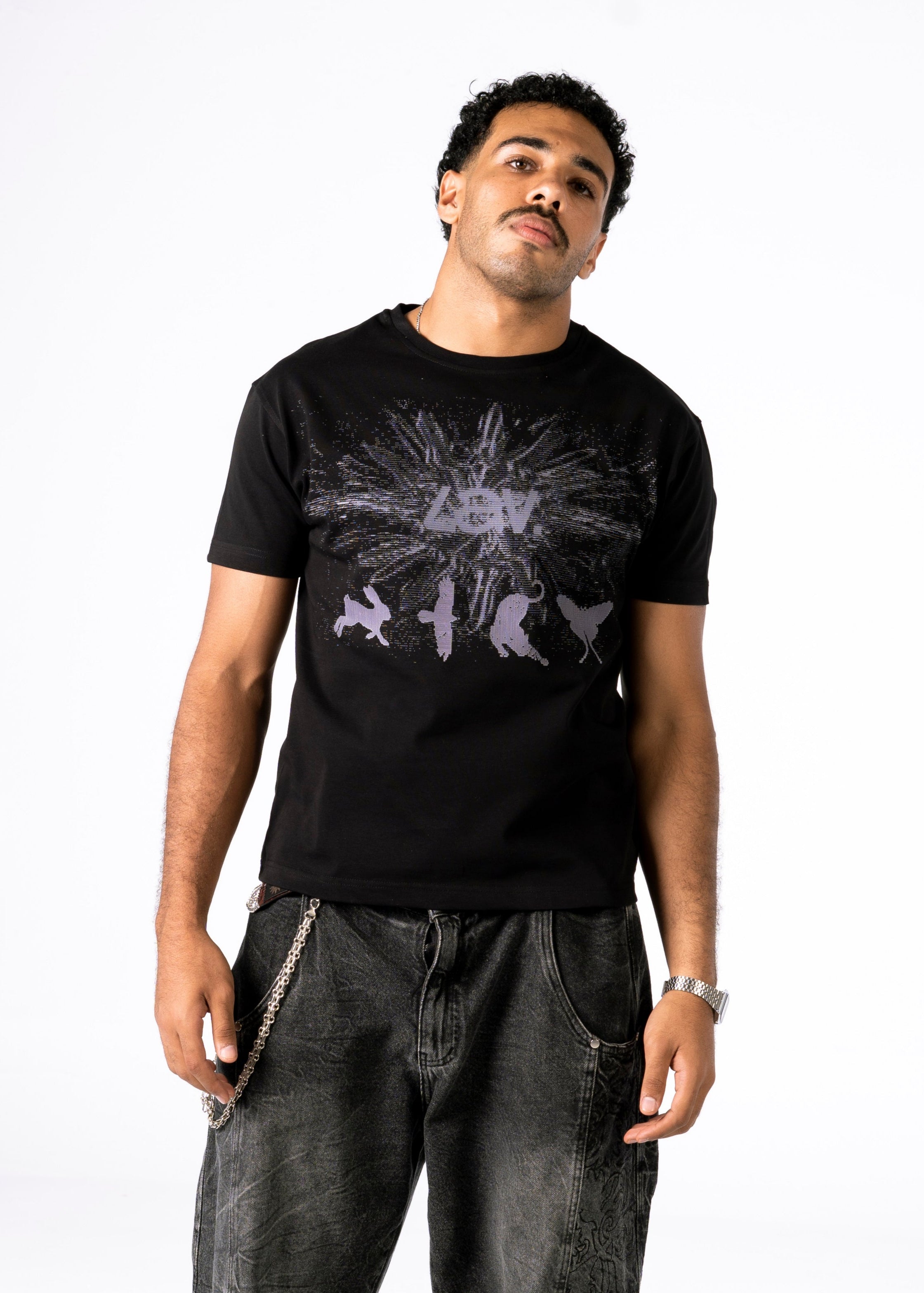 Man wearing a black t-shirt with a graphic design and dark jeans on a white background
